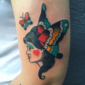 Get this stunning traditional tattoo of a butterfly and woman on your upper arm by Phil Botha. Perfect for those who love classic tattoo styles.