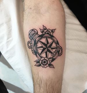 Explore new directions with this intricate forearm tattoo by Natalie Lucia, featuring a compass, steering wheel, and delicate flower designs.