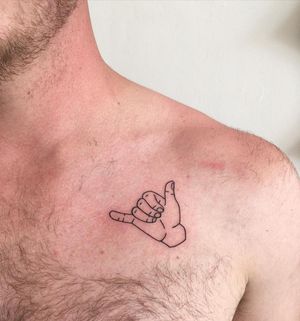 Get a fine line illustrative hand Hang Loose tattoo by Natalie Lucia for a stylish chest piece.