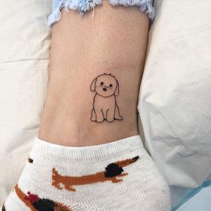 A delicate and intricate fine line tattoo of a dog, beautifully designed by the talented artist Natalie Lucia, perfect for ankle placement.