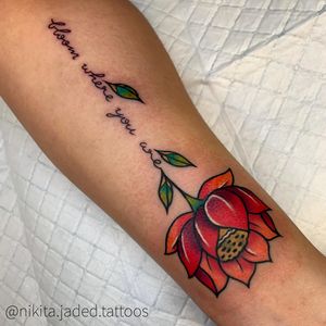 Elegant forearm tattoo by Nikita Jade Morgan featuring a delicate flower and small lettering quote in fine line illustrative style