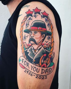 Get a classic upper arm tattoo featuring a man with a moustache, rope, hat, and horseshoe with a meaningful quote in traditional style by Phil Botha.