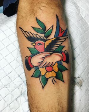 Unique forearm tattoo by Phil Botha featuring traditional style bird, flower, and hand motifs.