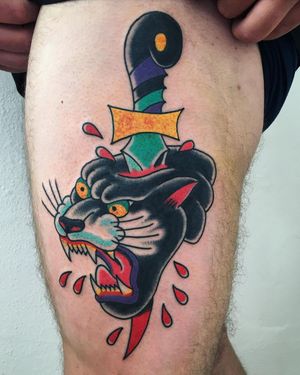 Bold and fierce traditional tattoo of a panther and a dagger on the upper leg, by artist Phil Botha.