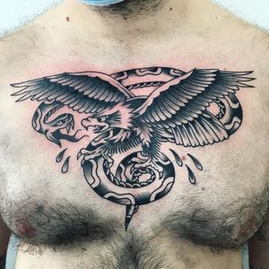 Bold blackwork chest tattoo featuring a snake and eagle in traditional style by artist Phil Botha.