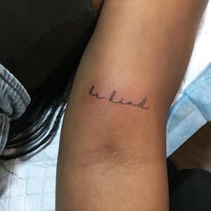 Sophisticated small lettering tattoo on upper arm with a meaningful quote by artist Natalie Lucia. Perfect for those seeking minimalistic, yet impactful ink.