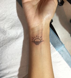 Stunning fine line forearm tattoo of a sun and beach scene, by talented artist Natalie Lucia.