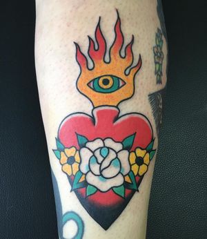 A stunning traditional tattoo on the forearm by the talented Phil Botha, featuring a beautiful combination of flower, heart, fire, and flames motifs.