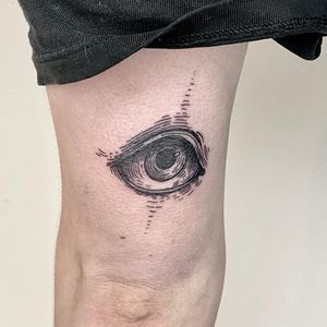 Intricate and mesmerizing upper leg tattoo of a realistic eye in black and gray by artist Lou. W.