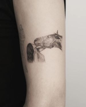 Beautiful black and gray illustrative forearm tattoo of a horse and girl, by Martyna Śliwka. Expressing the bond between nature and humanity.