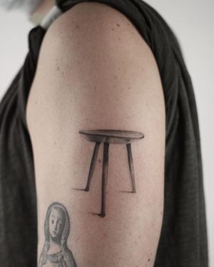 Get a stunning black and gray illustrative tattoo of a table by tattoo artist Dawid Szubert. Perfect for those who appreciate realism and detailed designs.