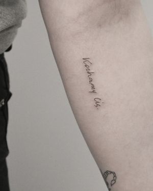 Elegant and delicate small lettering tattoo by Martyna Śliwka on forearm. Perfect for a subtle and meaningful touch.