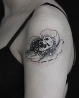 Illustrative design by Martyna Śliwka combining a delicate flower with a bold skull motif on the upper arm.