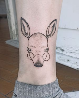 Elegantly detailed blackwork tattoo featuring a deer wearing glasses, expertly crafted by Lena Dabska on the lower leg.