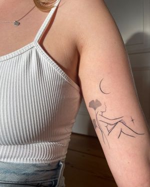 Elegant fine line tattoo on upper arm featuring a moon, star, flower, and a woman, beautifully illustrated by artist Dawid Szubert.