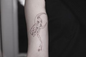 Graceful woman embracing the moon in intricate blackwork and fine line style on upper arm. Stunning design by talented artist.