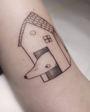 Illustrative blackwork tattoo on arm by Lena Dabska, featuring a detailed dog and house design.