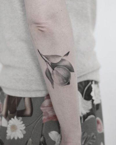 Martyna Śliwka's illustrative orange tattoo on forearm combines realism and blackwork styles for a striking design.