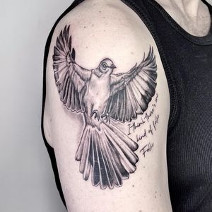 Incorporate realism with small lettering in this captivating upper arm tattoo by Lou. W., featuring a bird and inspiring quote.