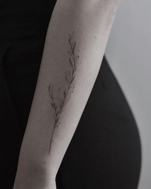 Beautifully detailed forearm tattoo of a delicate flower and sprig, done in fine line style by Martyna Śliwka.