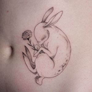 Elegant blackwork and fine line design by Lena Dabska featuring a rabbit surrounded by intricate flower details on the stomach.