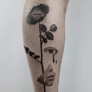 Stunning lower leg tattoo of a woman shedding tears surrounded by intricate blackwork floral designs. By Dawid Szubert.