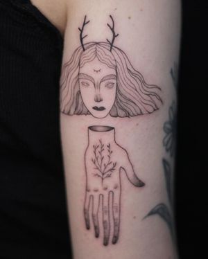 Check out this unique blackwork and fine line upper arm tattoo of a woman with horns and a hand by Lena Dabska.