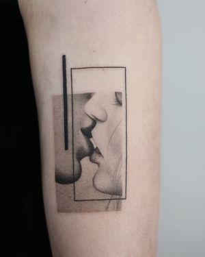Illustrative upper arm tattoo by Dawid Szubert featuring a realistic blackwork design of a woman and a kiss pattern.