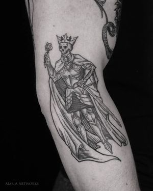 Mara's blackwork and fine line masterpiece features a skeletal king holding a sword, adorned with a crown, beautifully illustrated on the knee.