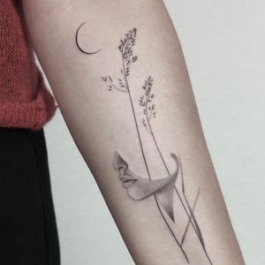 Dawid Szubert's fine line and realistic tattoo features a captivating blend of moon, woman, floral elements on the forearm.