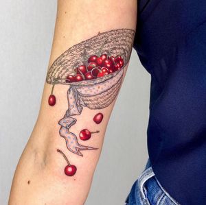 Vibrant upper arm tattoo featuring a stylish fruit hat design with cherries by Magdalena Sawicka.