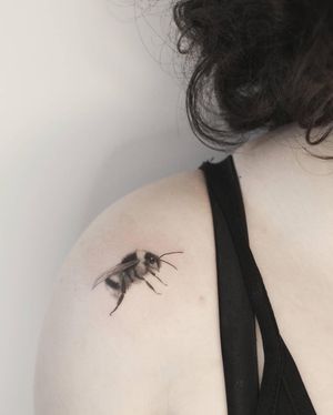 Detailed black and gray illustrative tattoo of a bee by Martyna Śliwka, perfectly placed on the shoulder.