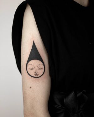 Illustrative upper arm tattoo featuring a sleek black drop design by talented artist Lena Dabska.