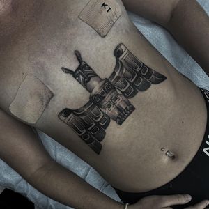 Unique blackwork illustration of totem with wings on stomach by Phillip Wolves. Bold and striking design.