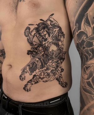 Experience the power of the fierce tiger and honorable samurai in this stunning Japanese style rib tattoo by FKM TATTOO.