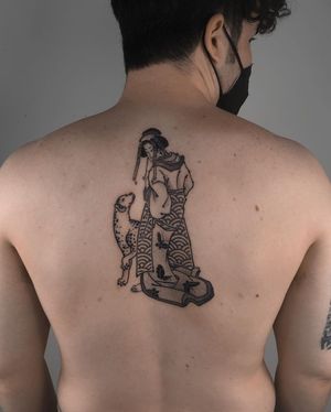 Get a stunning blackwork and fine line tattoo featuring a dog and geisha on your upper back by FKM TATTOO.