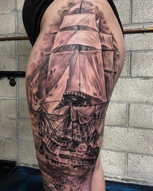 Get a stunning black and gray ship tattoo on your upper leg in Long Beach, showcasing intricate details and artistic skill.