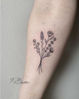 Elegant blackwork piece by tattoo artist Patrick Bates featuring a delicate flower sprig design on the forearm.