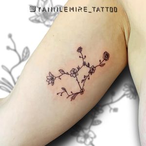 A stunning blackwork and fine line tattoo on the upper arm, featuring a beautiful combination of a flower and DNA motif, created by the talented artist Yann.