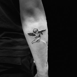 Fine line blackwork tattoo featuring a gun and angel wings, by the talented artist Niklas Fogh.