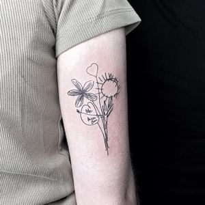 Fine line and small lettering upper arm tattoo featuring a beautifully detailed flower and a meaningful quote, designed by Lars.
