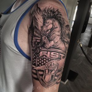 Unique upper arm tattoo featuring a realistic blackwork horse with tree and hand elements, along with an American flag and meaningful quote by Jones.