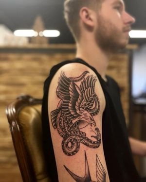 Harness the power of these ancient symbols with a striking blackwork design by Yura. The intricate details of the snake and eagle create a dynamic and powerful tattoo.
