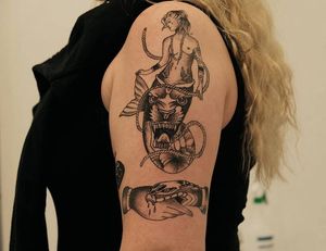 Unique tattoo featuring a snake, tiger, mermaid, woman, hand, rope, and necklace in fine line style on the upper arm.