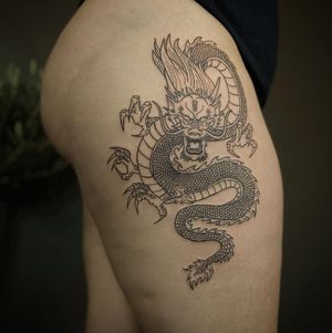 Bold blackwork design of a Japanese dragon by Yura, featuring fine line details and illustrative style on the upper leg.