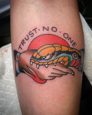 Eddy Ospina's illustrative tattoo features a snake wrapped around a hand with a powerful quote, perfect for the forearm.