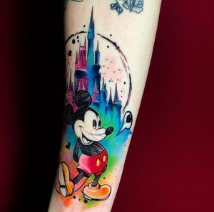 Celebrate the magic of Disney with this stunning watercolor tattoo by Marcel Oliveira. Mickey Mouse and Cinderella's Castle beautifully illustrated in vibrant colors.