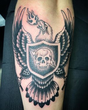Bold blackwork design by Eddy Ospina featuring an eagle, skull, shield, and fire motifs.