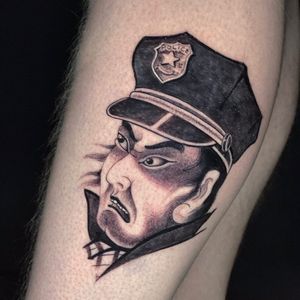 A realistic and illustrative tattoo of a police cap on a man's lower leg, crafted by renowned artist Ami James.