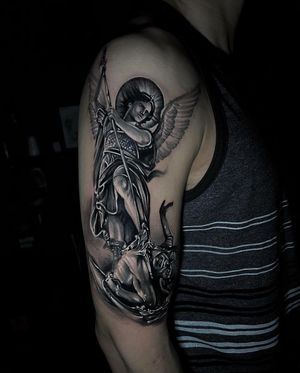 A stunning black and gray illustrative tattoo of a devil and angel with wings on the upper arm, by Marcel Oliveira.